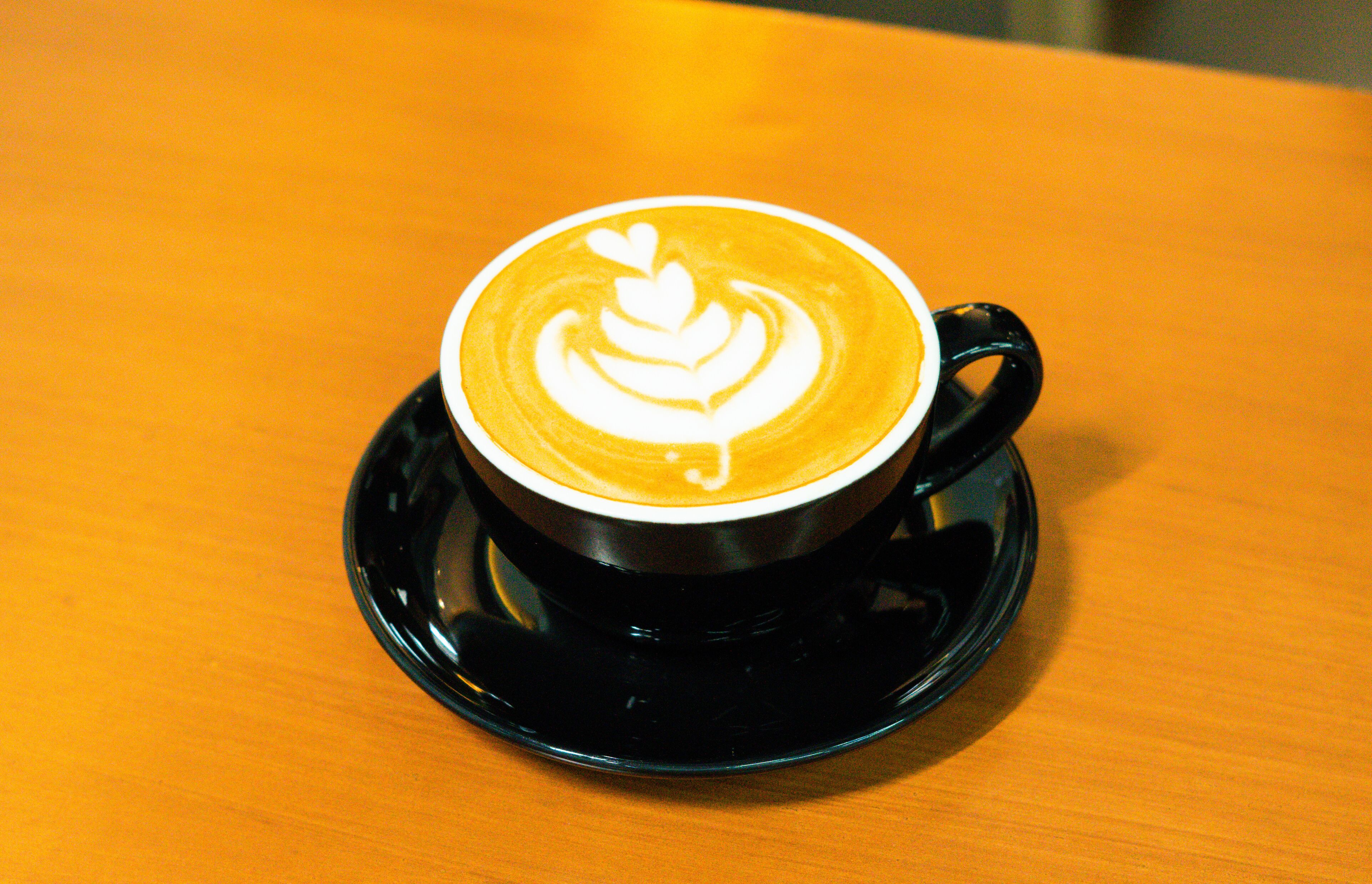 Una taza de café con arte de latte en un plato.