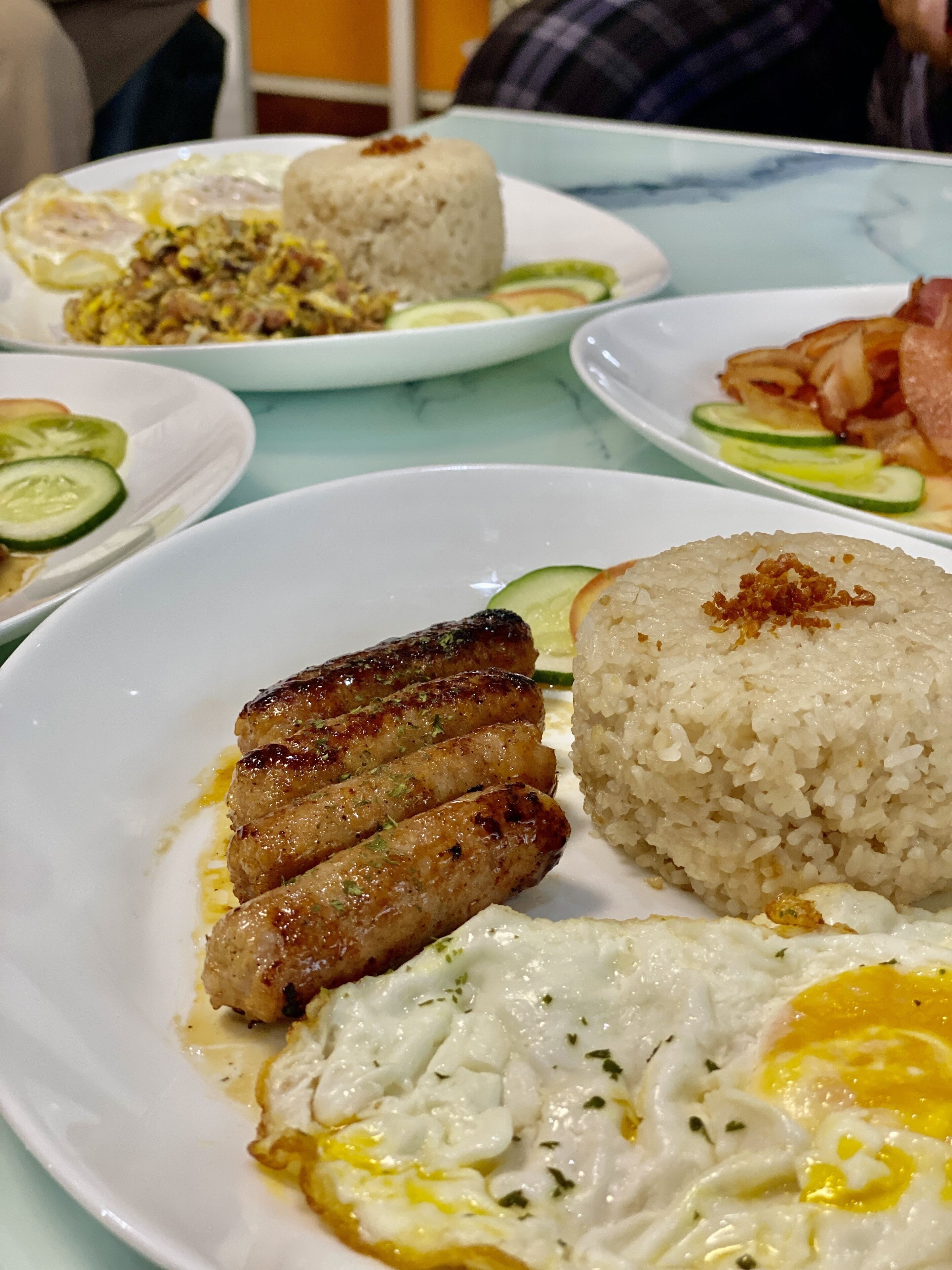 A table with various dishes including fried rice, grilled meat, and eggs.