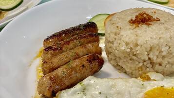 Una mesa con diversos platos, incluyendo arroz frito, carne a la parrilla y huevos.