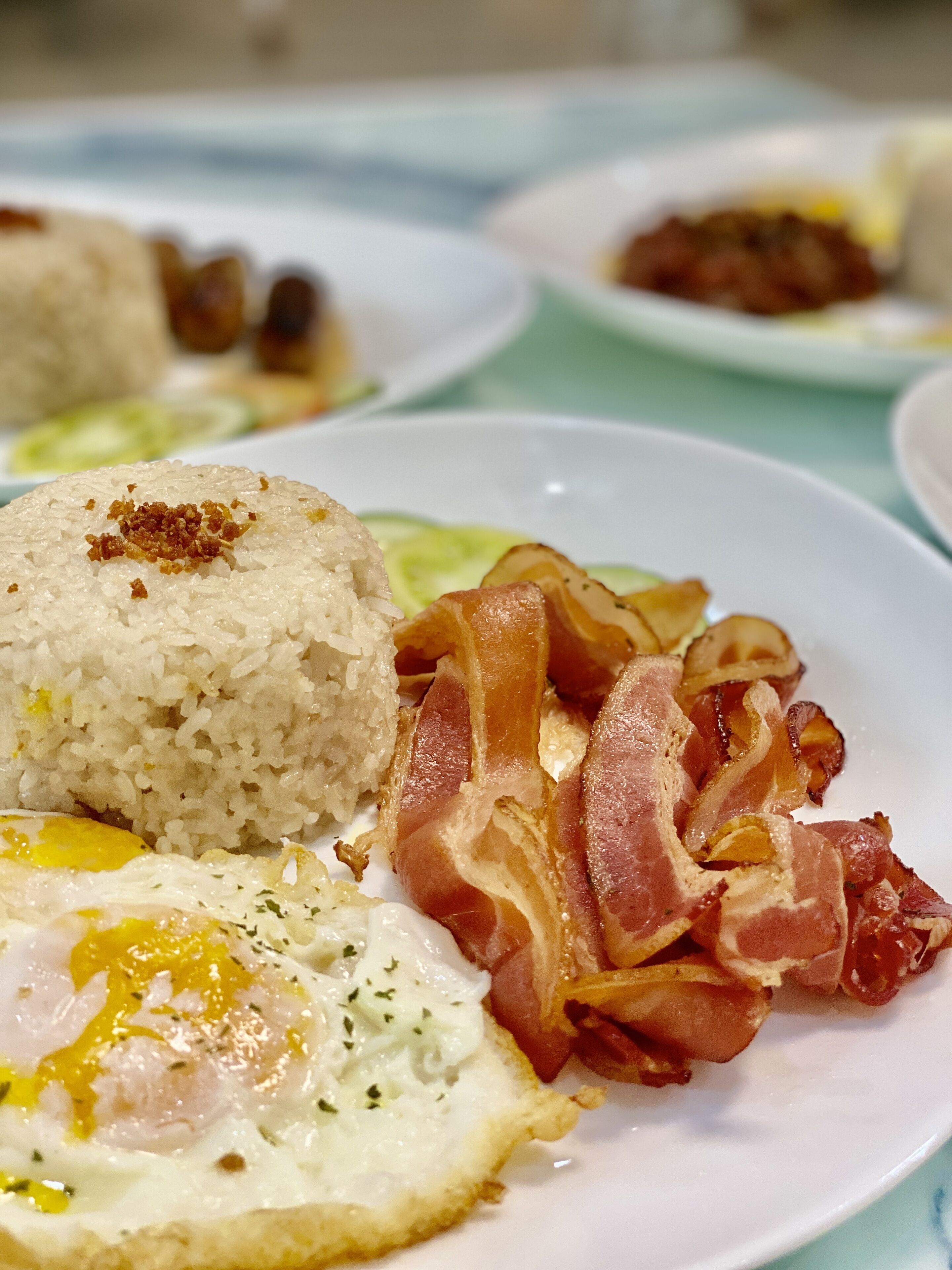 Un plato de arroz, tocino y un huevo frito.