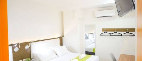 Una habitación de hotel con cama, mesita de noche, televisor y escritorio con silla.
