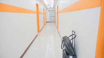 Een hotelgang met oranje accenten op de muren en een koffer aan de rechterkant.