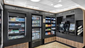 A self-service beverage and coffee station with refrigerated beverage dispensers, snack shelves, and a coffee machine. - Marriott BeachPlace - Best Location in Ft Lauderdale Beach | Walk to everything (Fort Lauderdale)