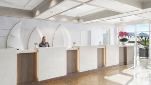 Una zona de recepción moderna con una recepcionista, un ventanal y vistas al exterior.
