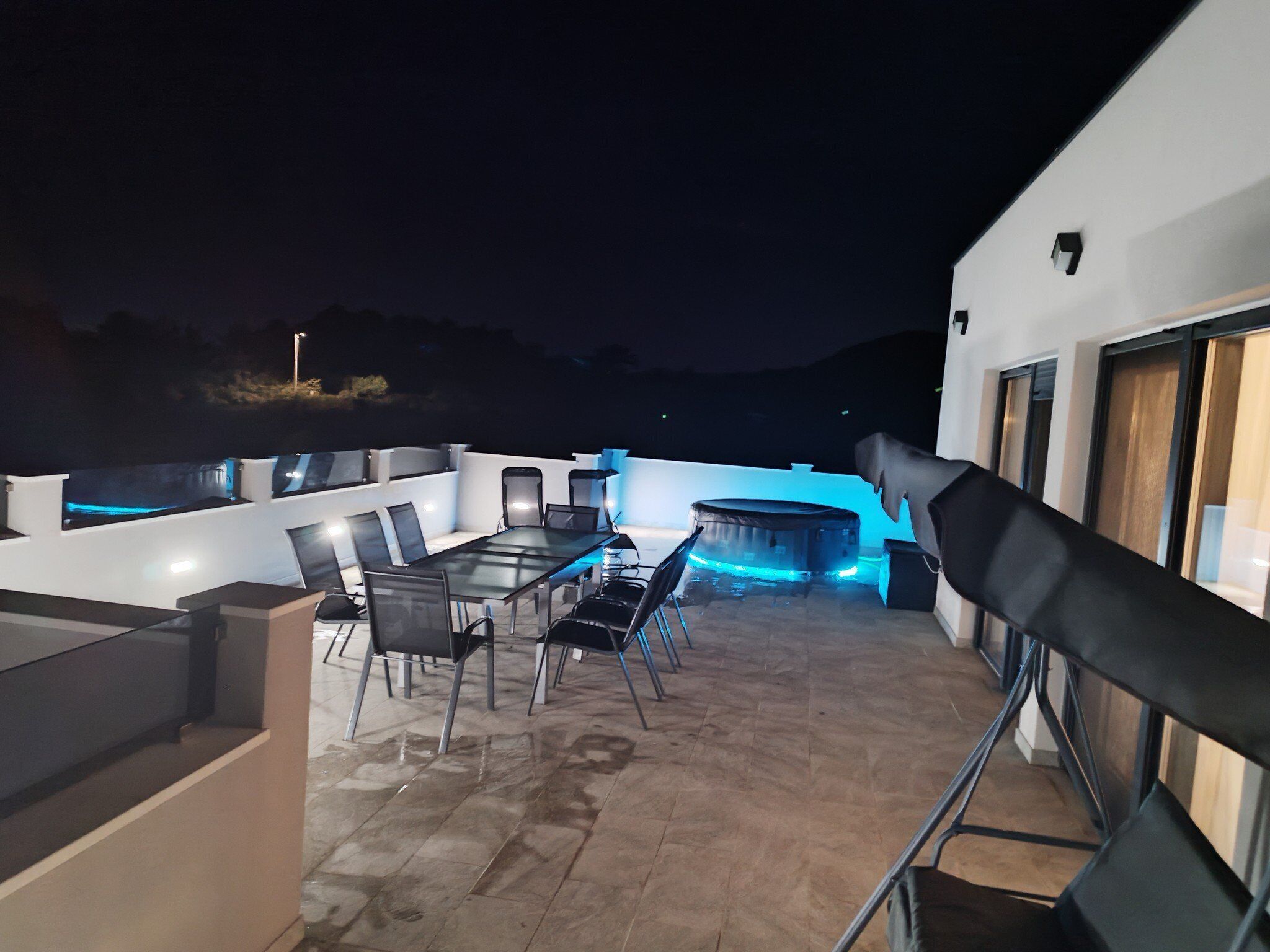 An outdoor patio area with a dining table and chairs, a barbecue grill, and a sofa.