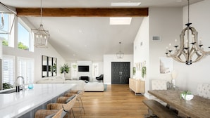 Una cocina amplia con una isla grande, piso de madera y luminarias modernas.