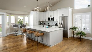 Una cocina amplia con una isla grande, muebles blancos y electrodomésticos modernos.