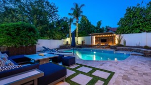 Un patio trasero con piscina, zona de estar y una terraza con chimenea.