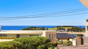 A coastal view with a clear sky, a beach, and a parking area. - MOON GLOW | Accom Holidays (TERRIGAL)