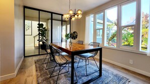 Ein moderner Essbereich mit Holztisch, schwarzen Metallstühlen und einer hängenden Leuchte.
