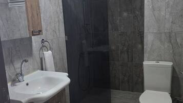 Un baño con lavamanos, inodoro y ducha.