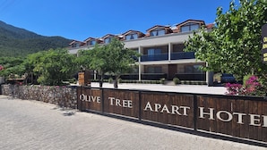 A modern two-story building with balconies, a stone wall, and a sign for Olive Tree Apart Hotel. - OLIVE TREE APART HOTEL (Koycegiz)