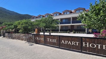 Situated in a hilly region, the Olive Tree Apart Hotel offers a scenic backdrop with lush greenery and flowering plants.