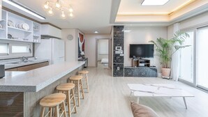 Une cuisine moderne avec un coin bar, une table à manger et un téléviseur.