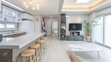 A modern kitchen with a bar area, a dining table, and a TV.