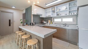 Une cuisine moderne dotée d’un îlot central, de tabourets de bar et d’étagères intégrées.