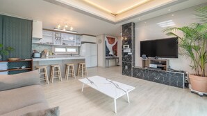 Une cuisine moderne avec des tabourets de bar, une table à manger et un téléviseur dans l’espace salon.