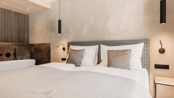 A modern bedroom with a large bed, a wooden slatted wall, and pendant lighting.