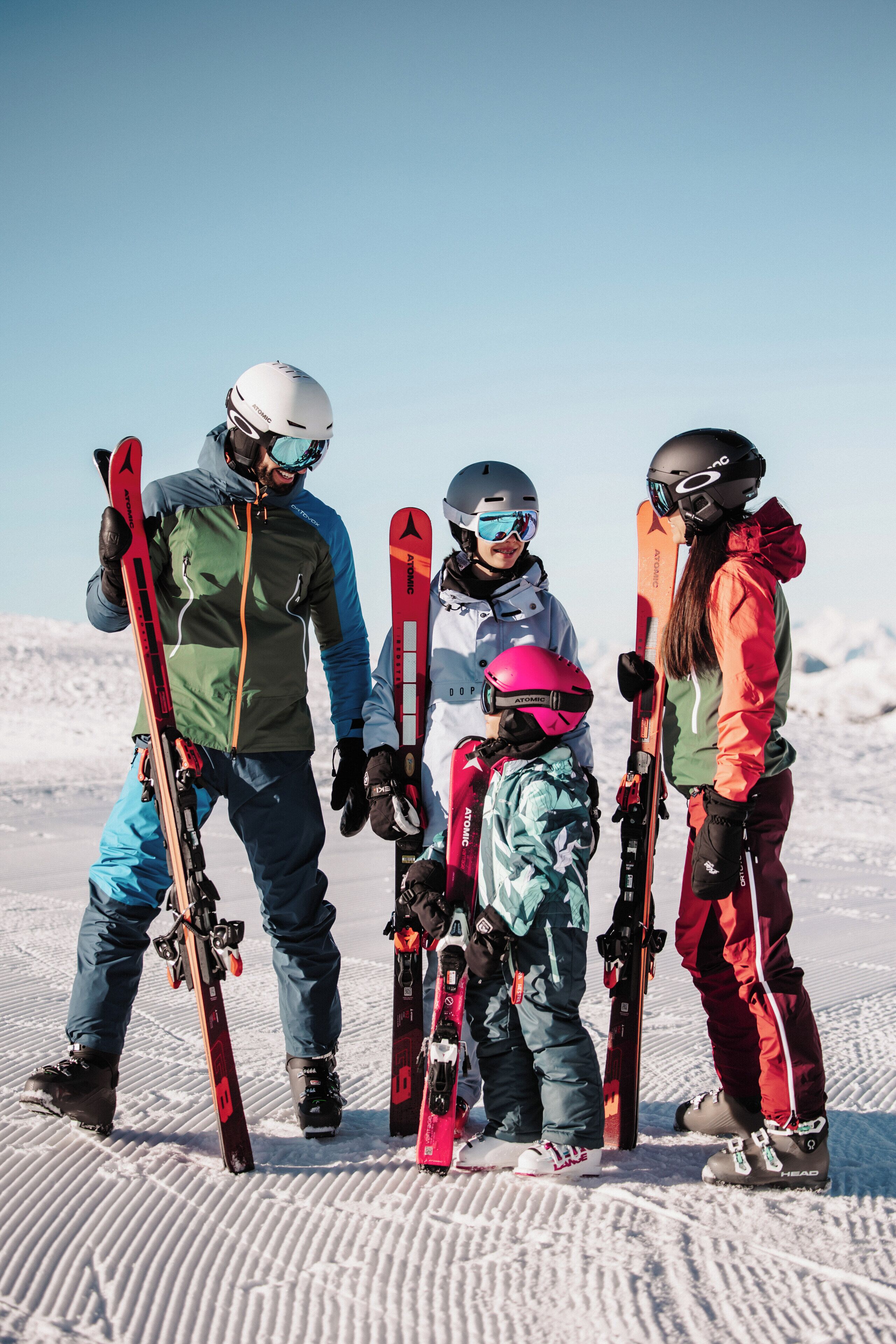 A group of people standing on a snowy surface, each holding skis.