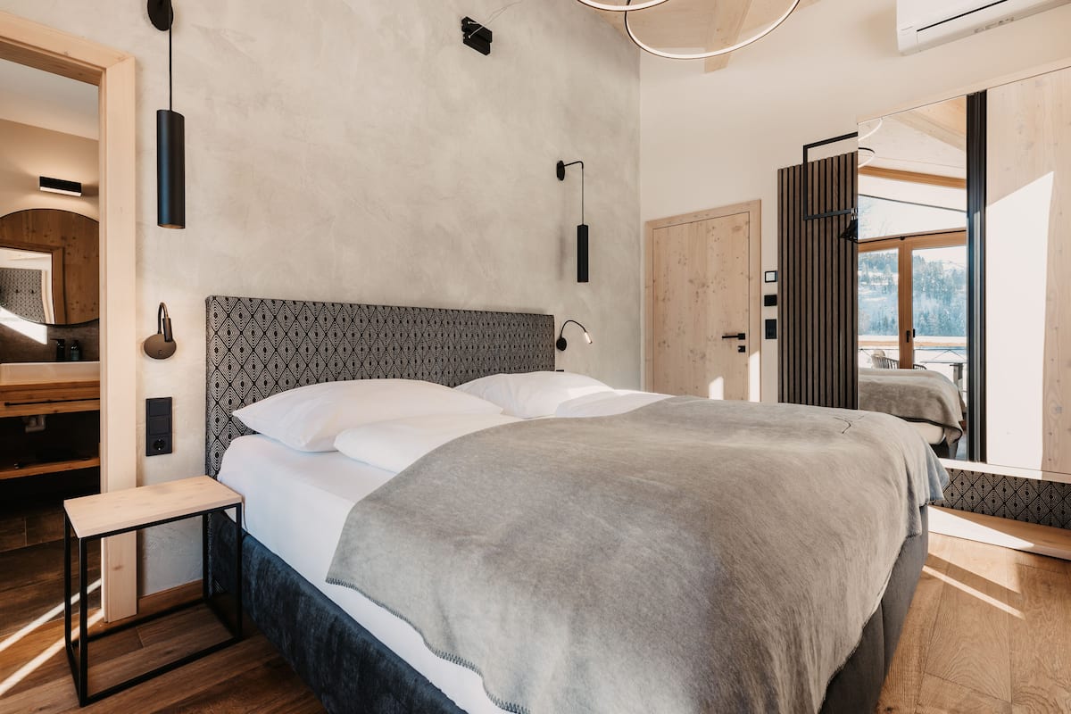 A modern bedroom with a large bed, a bedside table, and a built-in bench.