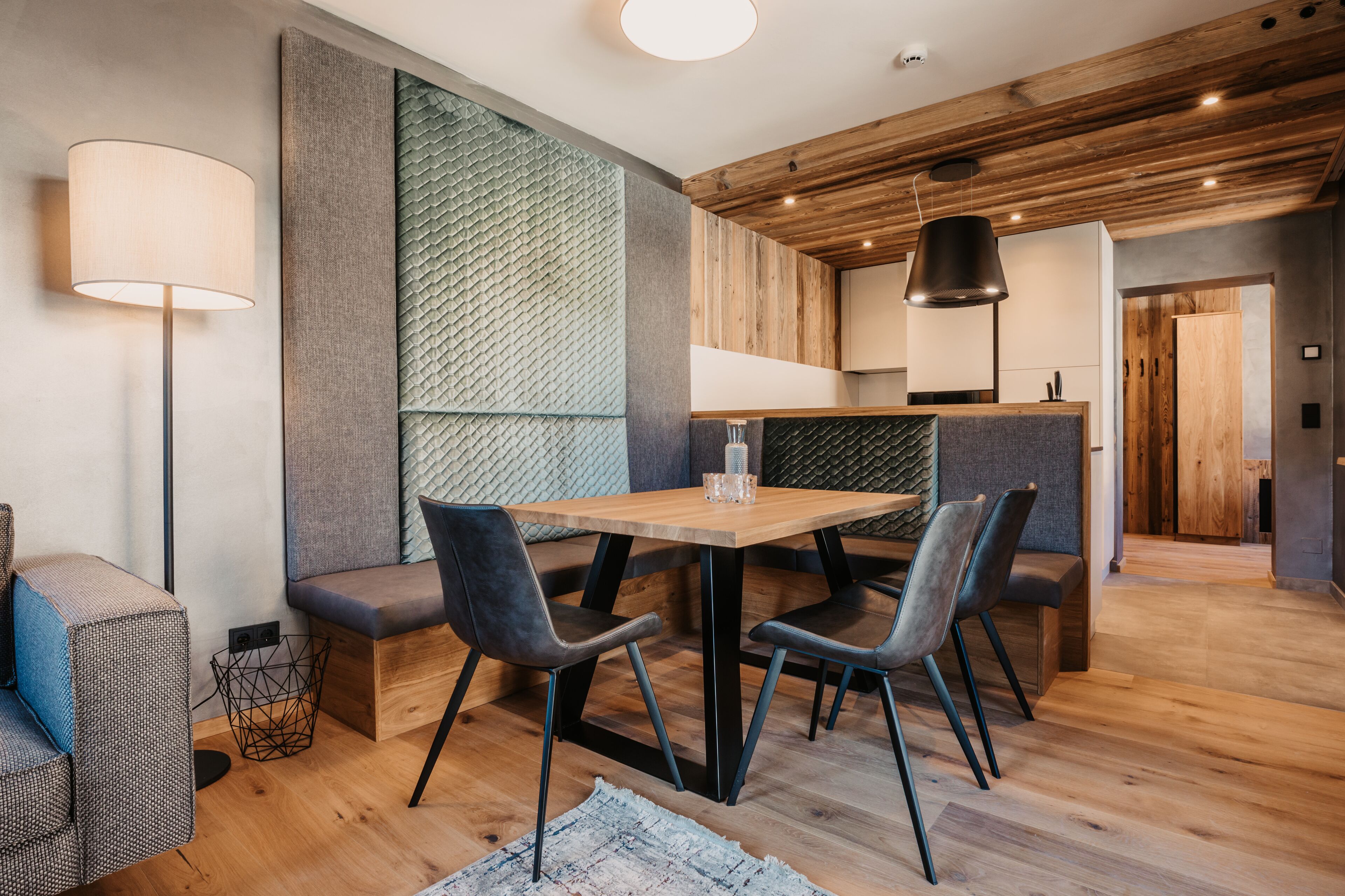 Un comedor moderno con una mesa de madera, sillas tapizadas de color gris y un banco.