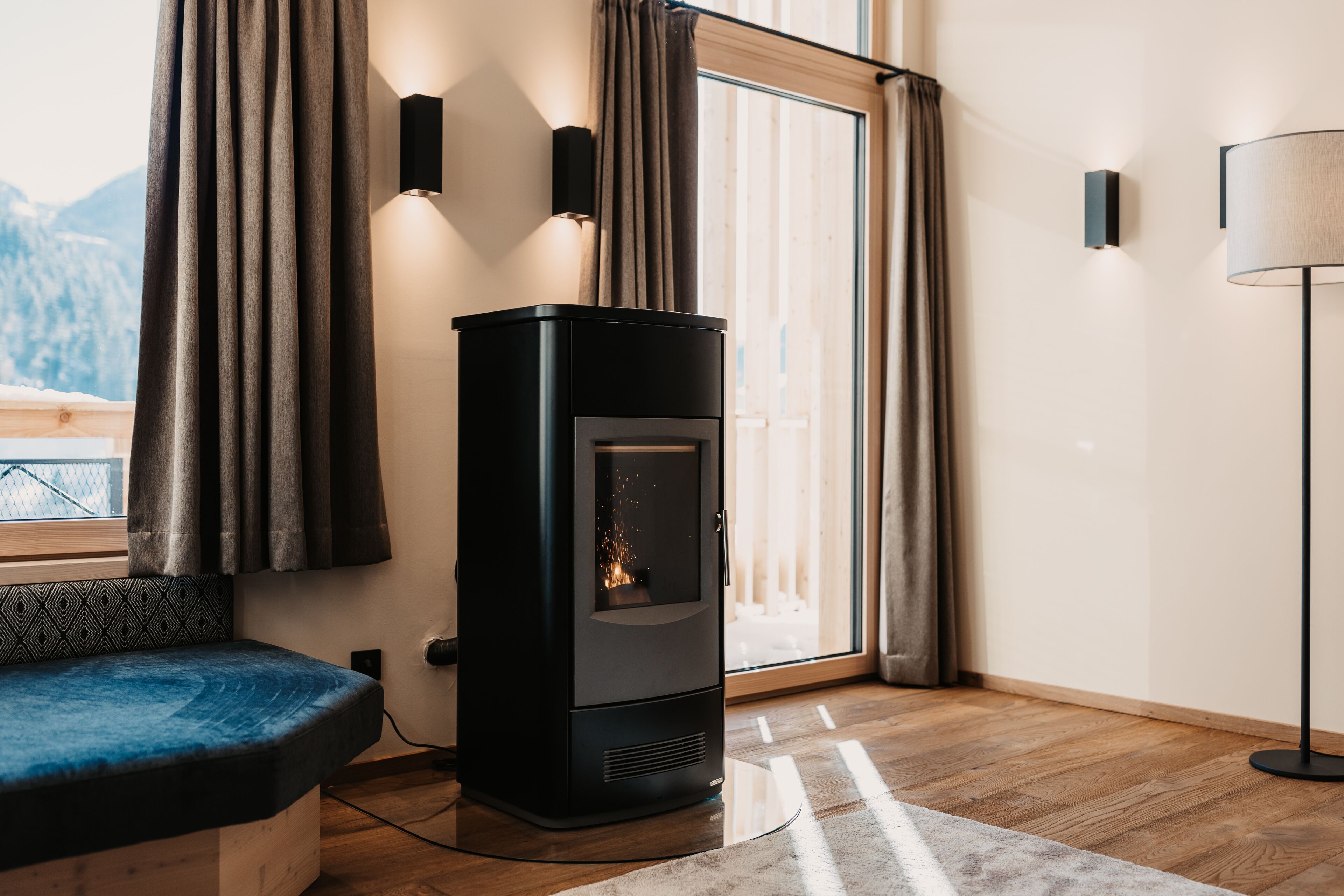 A modern living room with a wood-burning stove, a sofa, and a lamp.