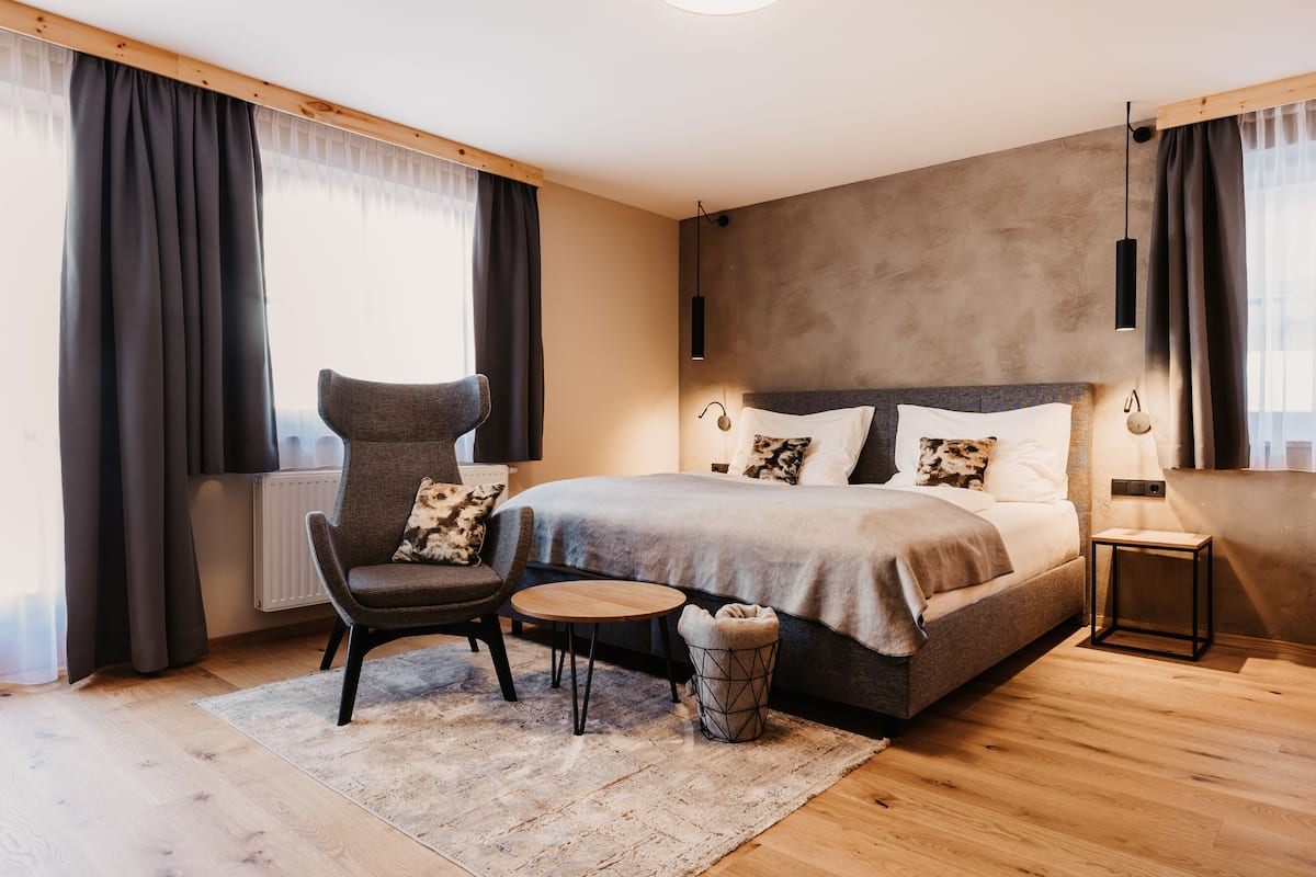 A modern bedroom with a large bed, a chair, a small table, and a rug.