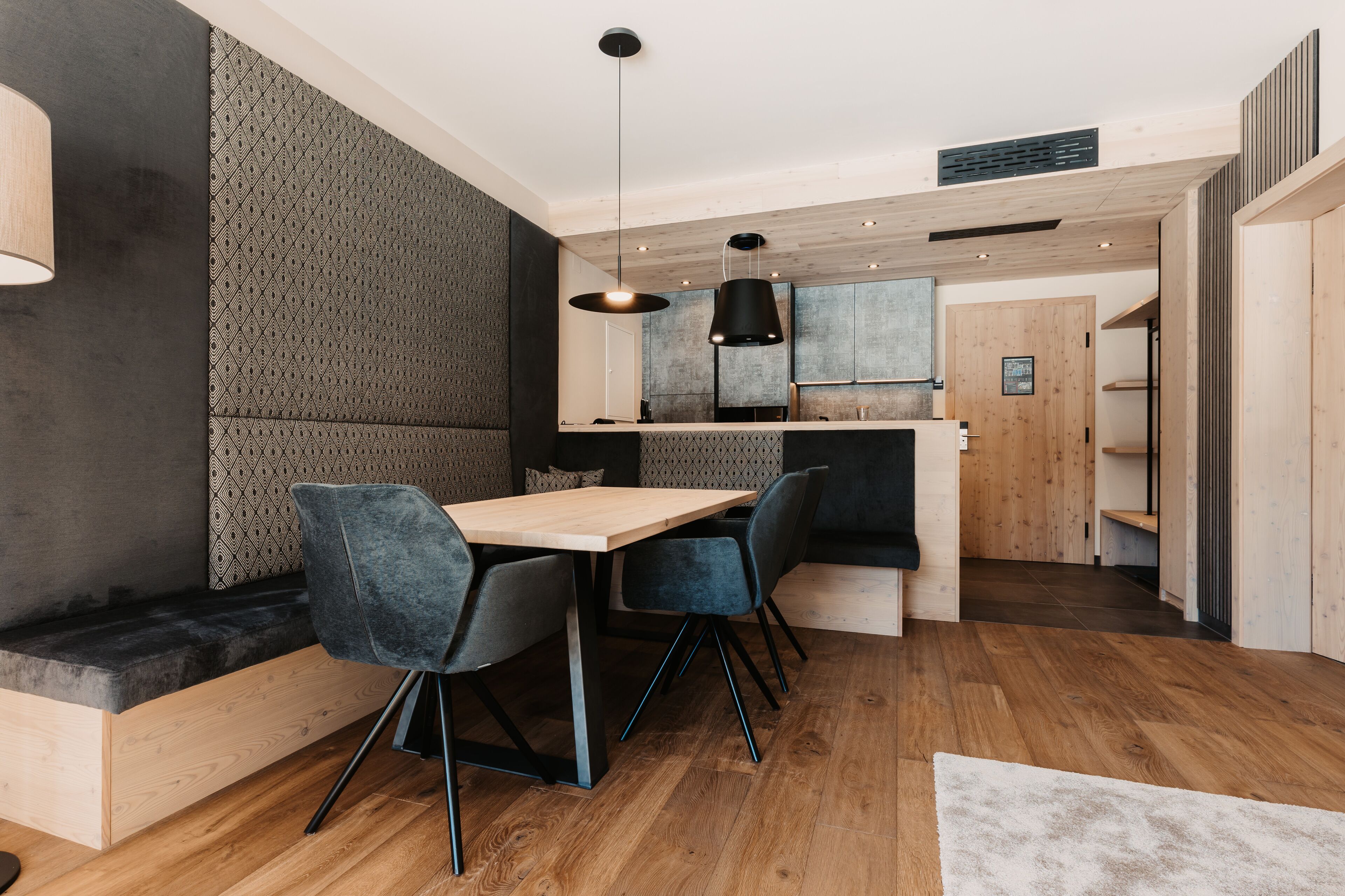 Una cocina moderna con armarios de madera, horno empotrado y comedor con mesa y sillas de madera.