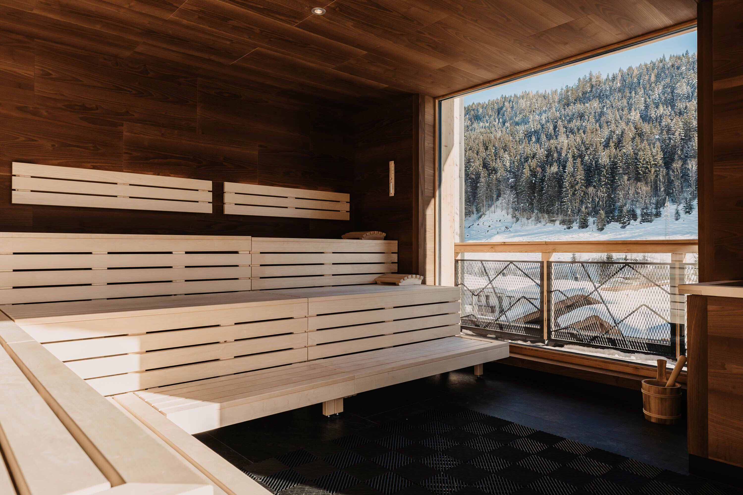 A wooden cabin interior with a large window offering a view of a snowy forest.