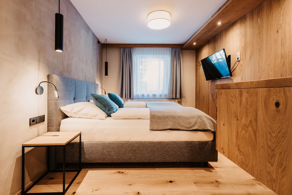 A modern bedroom with a bed, bedside table, and a television mounted on the wall.