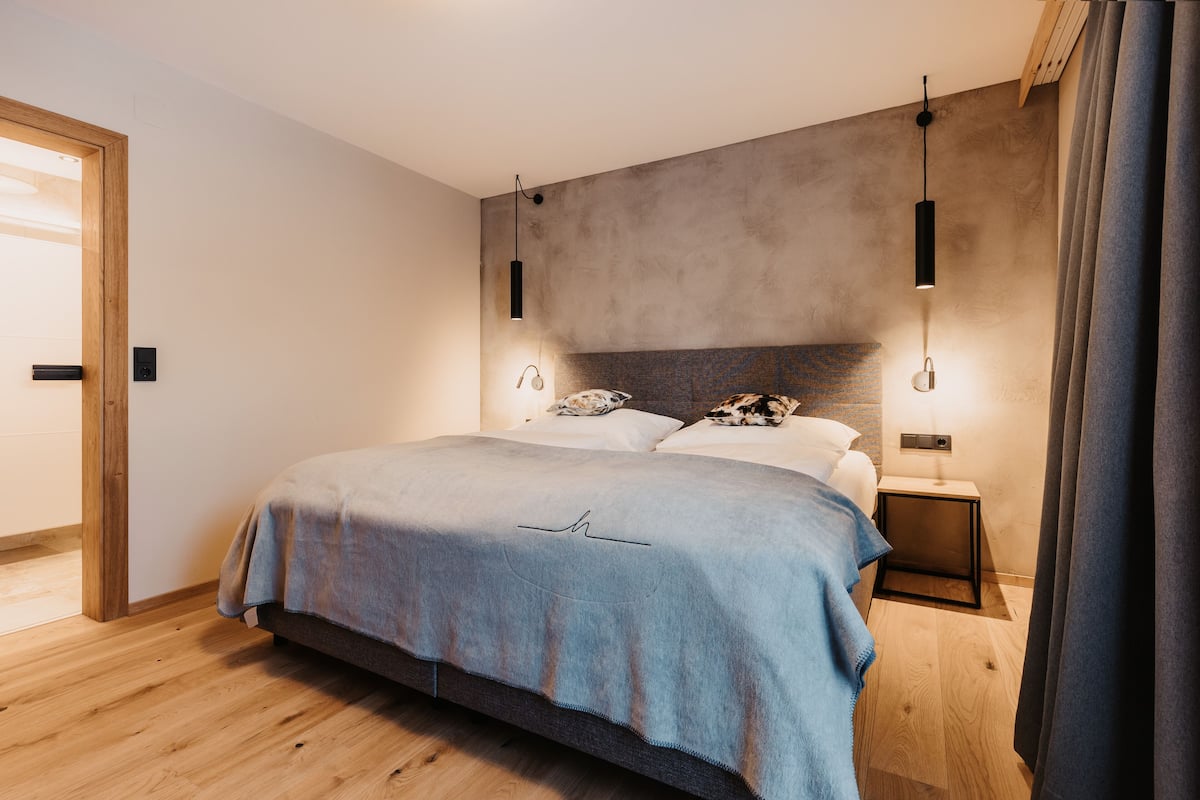 A modern bedroom with a bed, bedside tables, and a headboard.