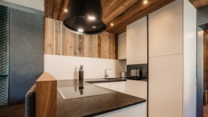 Una cocina moderna con techo de madera, una isla integrada con encimera negra y armarios blancos.