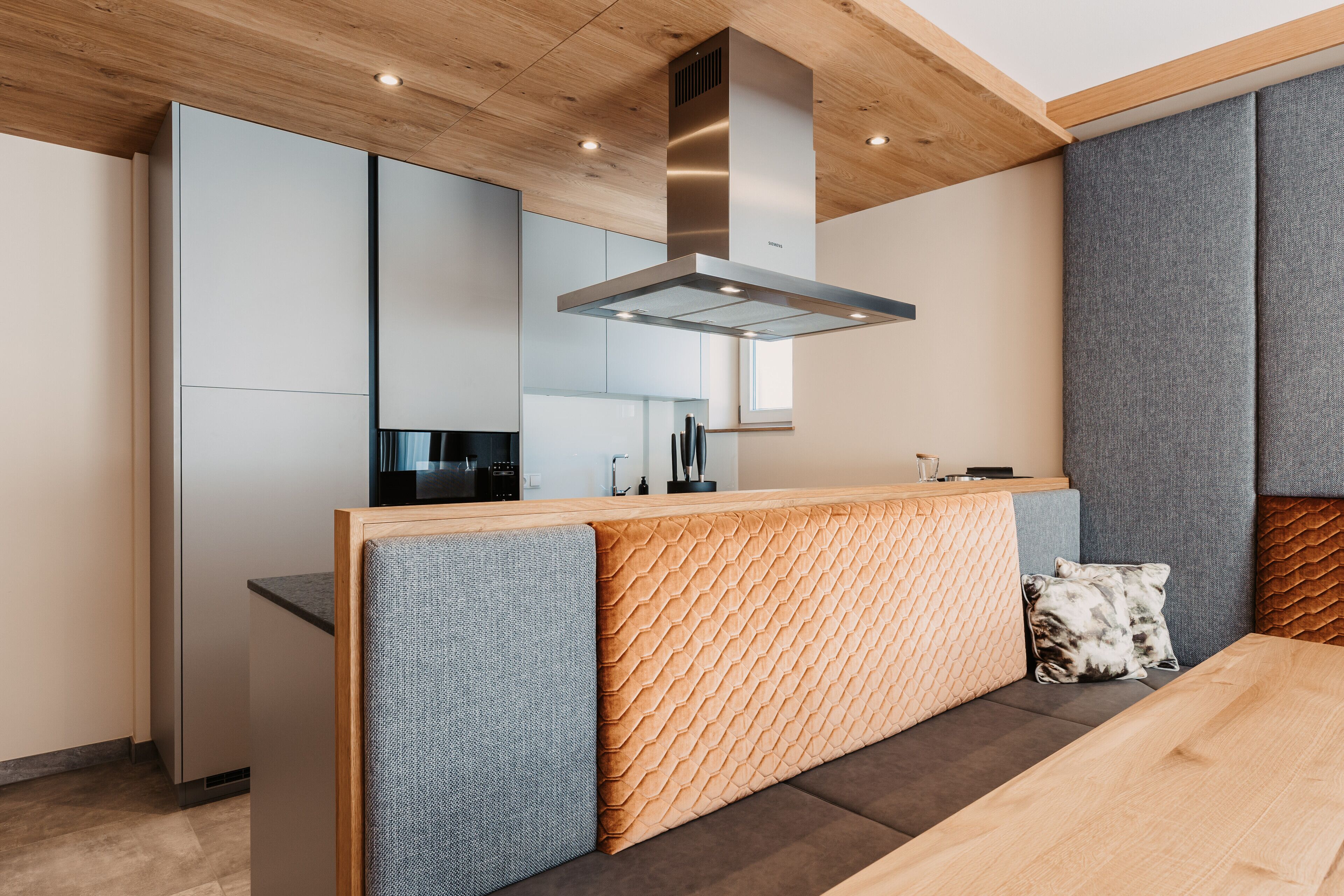 Una cocina moderna con techo de madera, electrodomésticos integrados y una isla central con asientos.