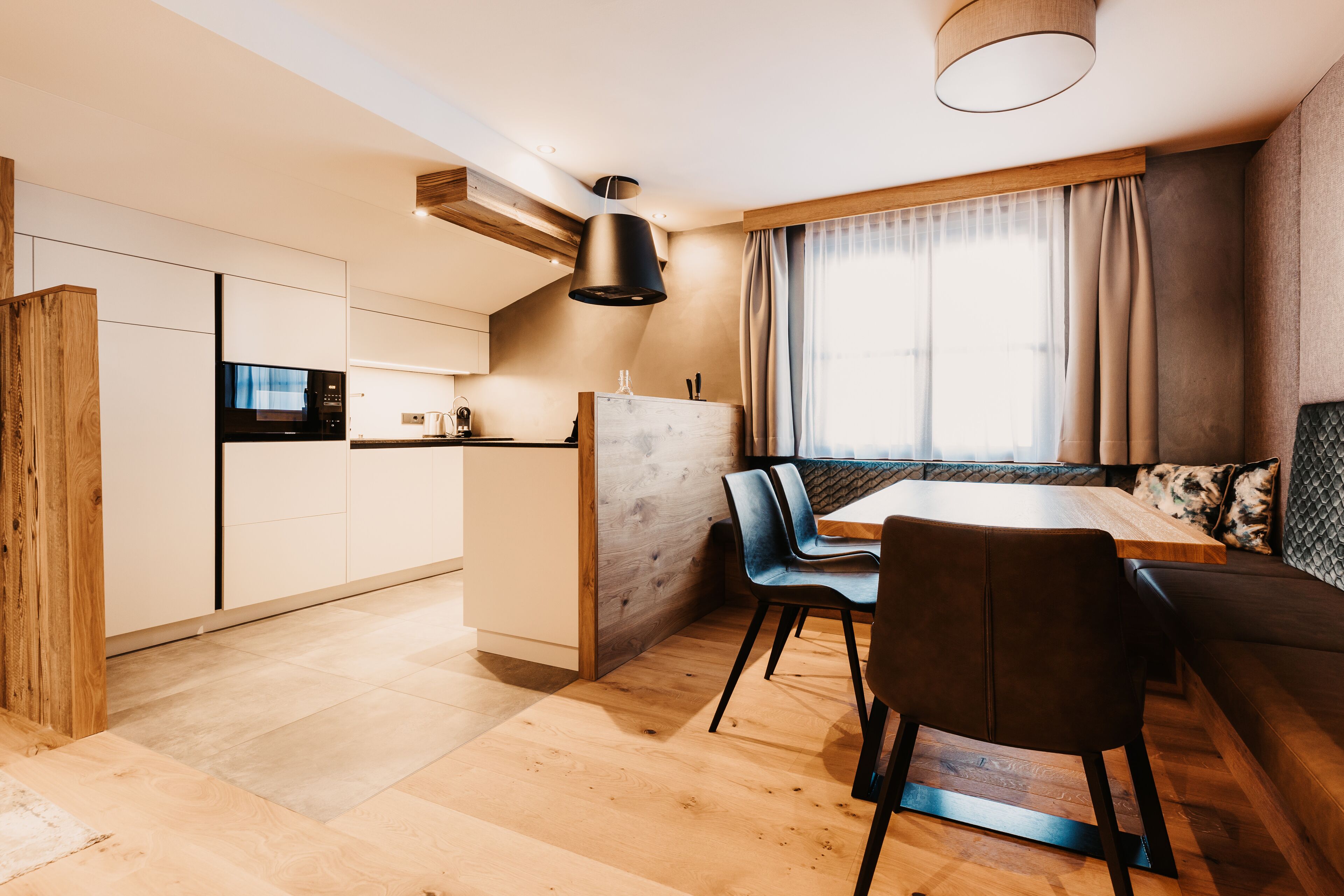 A modern kitchen with white cabinets, a black microwave, and a wooden dining table with chairs.