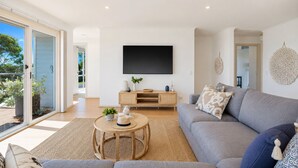 A modern living room with a grey sofa, a wooden coffee table, and a flat-screen TV mounted on the wall. - Seaview Cowes by Ready Set Stay (Cowes)