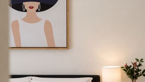 A bedroom with a bed, pillows, a bedside table with a lamp, a vase with flowers, and a framed artwork on the wall. - Seaview Cowes by Ready Set Stay (Cowes)
