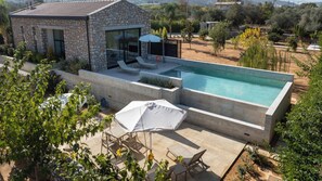 Uma casa moderna com piscina, fachada de pedra e área de estar externa.