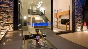 Un interior moderno con una pared de piedra, una zona de comedor con manteles azules y una botella de vino sobre una mesa.