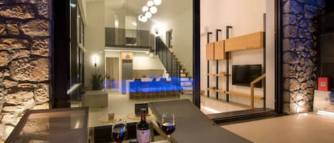 Un intérieur moderne avec un mur en pierre, un coin repas avec des nappes bleues et une bouteille de vin posée sur une table.
