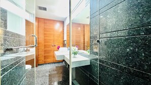 Une salle de bain moderne avec une porte en bois, un lavabo blanc et un grand miroir.