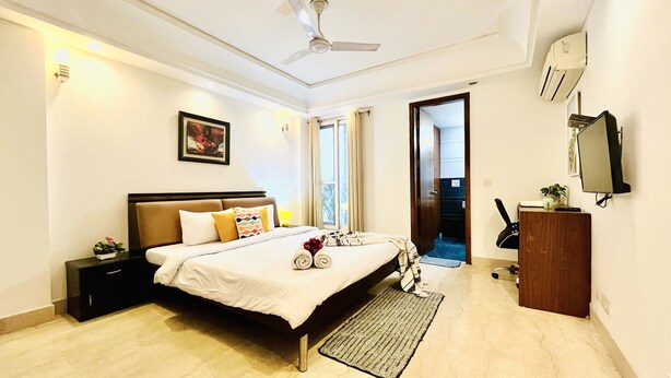 Une chambre d’hôtel comprenant un lit, une table de chevet, une commode, un bureau, une chaise et un téléviseur.