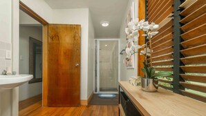 A modern bathroom with a wooden door, a white sink, and a shower area.
