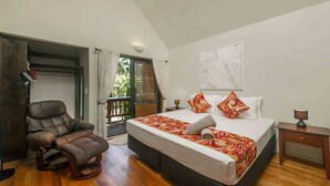A bedroom with a bed, a reclining chair, a nightstand, and a view of the outdoors.