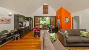 A modern kitchen with dark cabinets, a wooden dining table, and a sofa with colorful cushions.