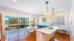 A modern kitchen with a central island, large windows, and a view of the outdoors. - Pretty Beach Bay Vista by HolidayCo. (PRETTY BEACH)