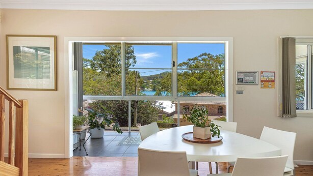 A dining area with a large window offering a view of a swimming pool and trees. - Pretty Beach Bay Vista by HolidayCo. (PRETTY BEACH)