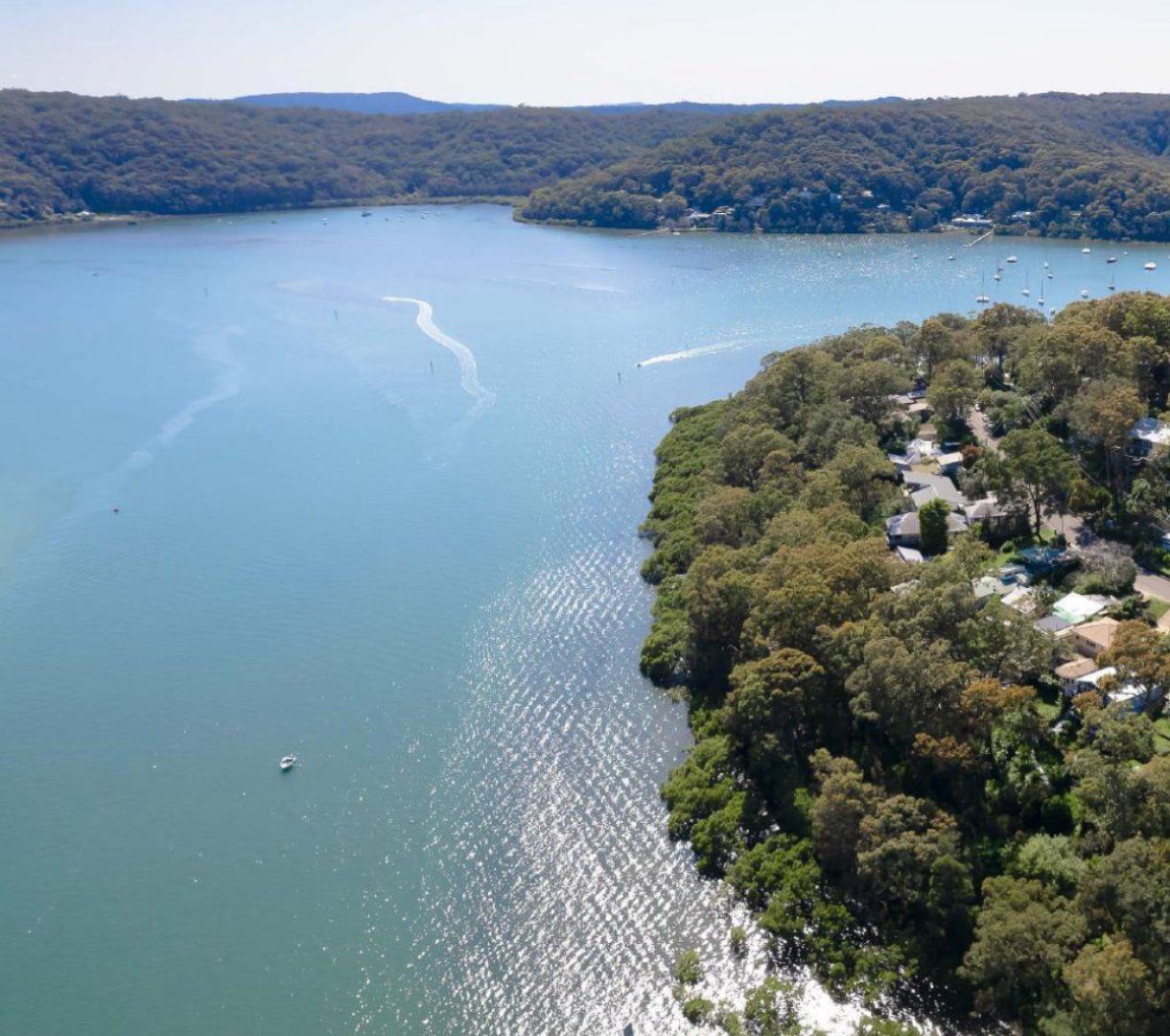Vue aérienne d’un quartier résidentiel avec des maisons situées le long de la 94e rue, entouré d’une forêt dense et bordé d’une grande étendue d’eau où se trouvent des bateaux.