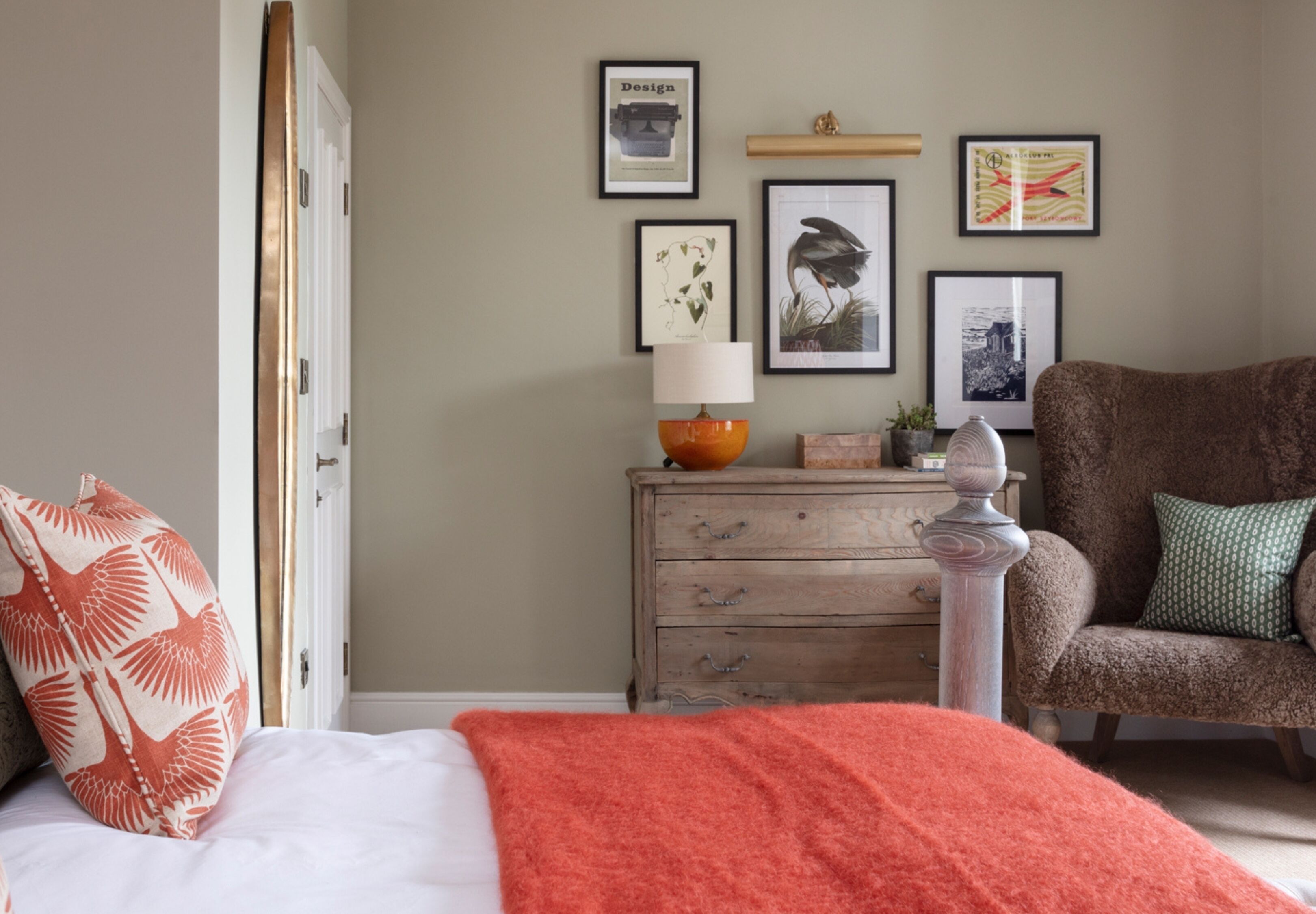 Een slaapkamer met een bed, een dressoir, een stoel en wanddecoratie.