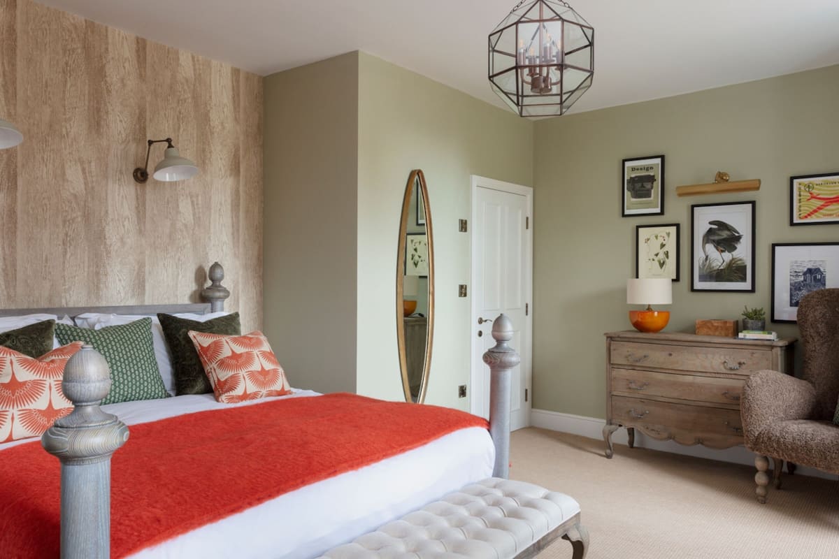 A bedroom with a bed, a dresser, a chair, and a mirror.