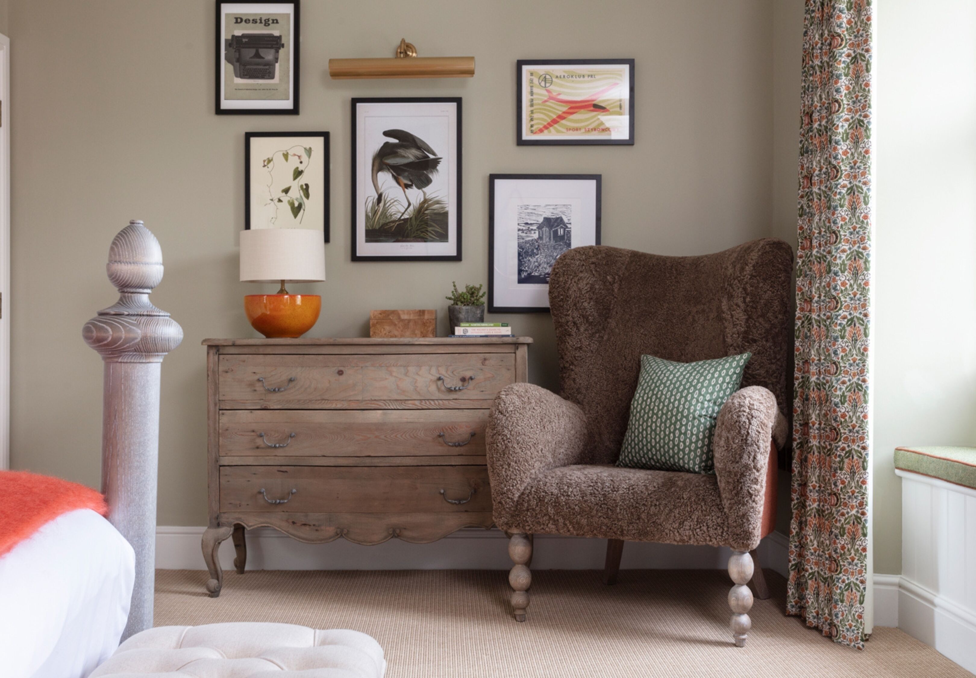 A cozy room with a wooden dresser, a plush armchair, and a decorative lamp.